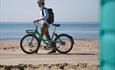 Man pushes his beryl bike along the seafront taking in the beach views