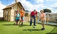 Mother and father watching their sons putt the ball on golf hole