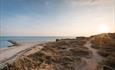 Sun rising over Hengistbury head beach and grassland