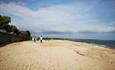 Wide shot of two people enjoying a walk out on the sand and shingle beach.