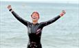 Woman with a happy face and hands in the air by the sea