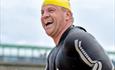 Man smiling with water droplets in the air and pier in the background