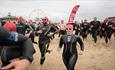 Lady in swim gear running with crowd down the beach